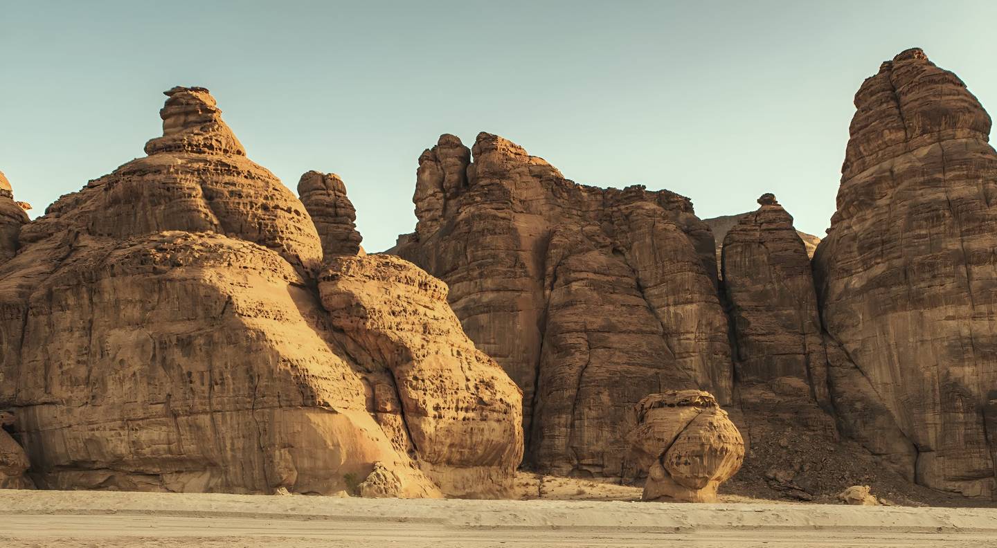 Sandstone cliffs rising above open desert sand