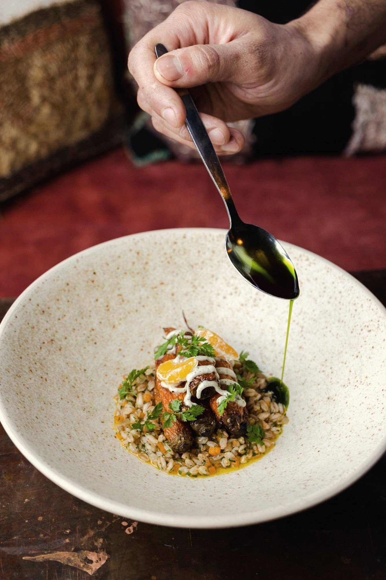 Chef finishing a dish with herb oil