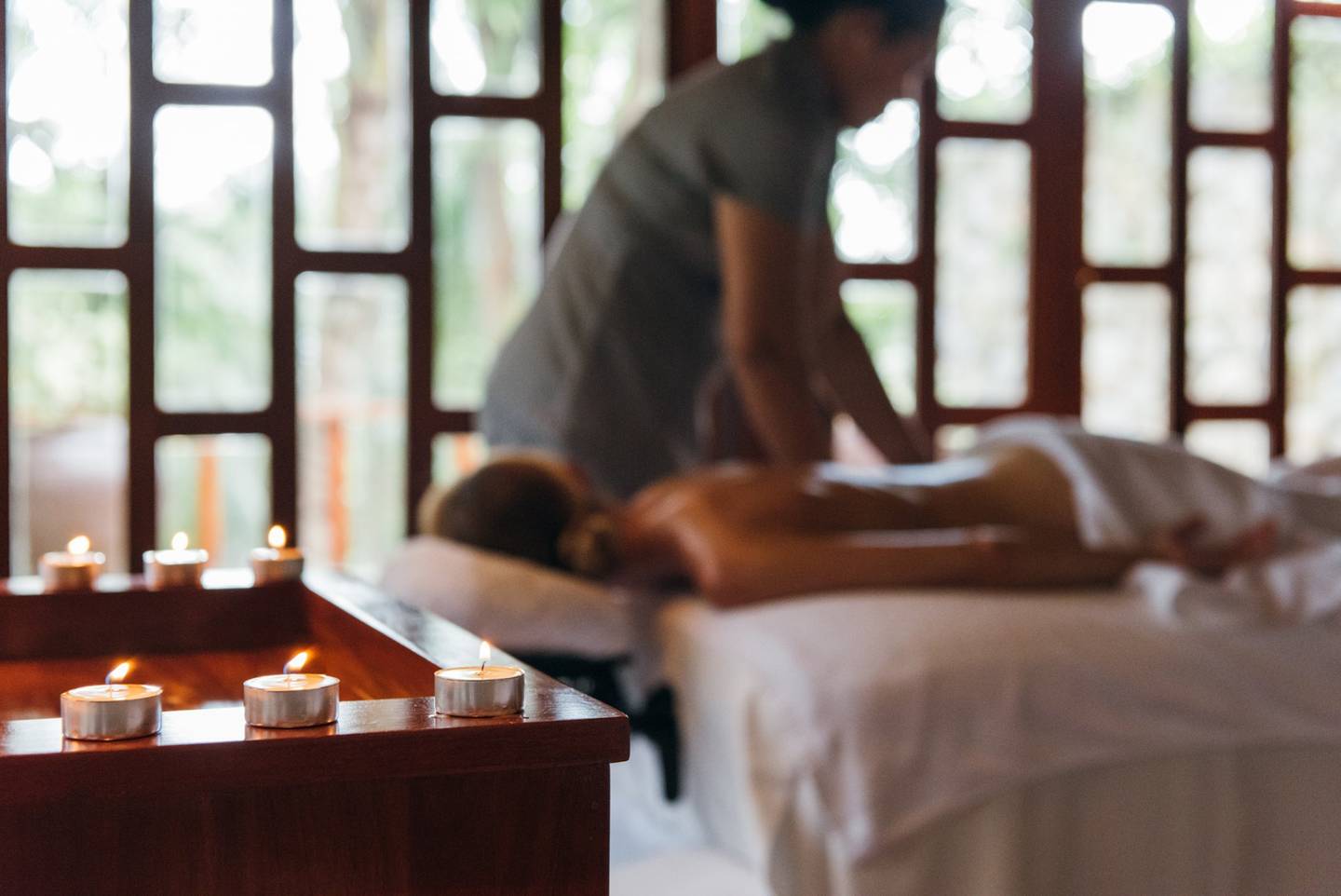 A candlelit spa treatment room with a massage in progress