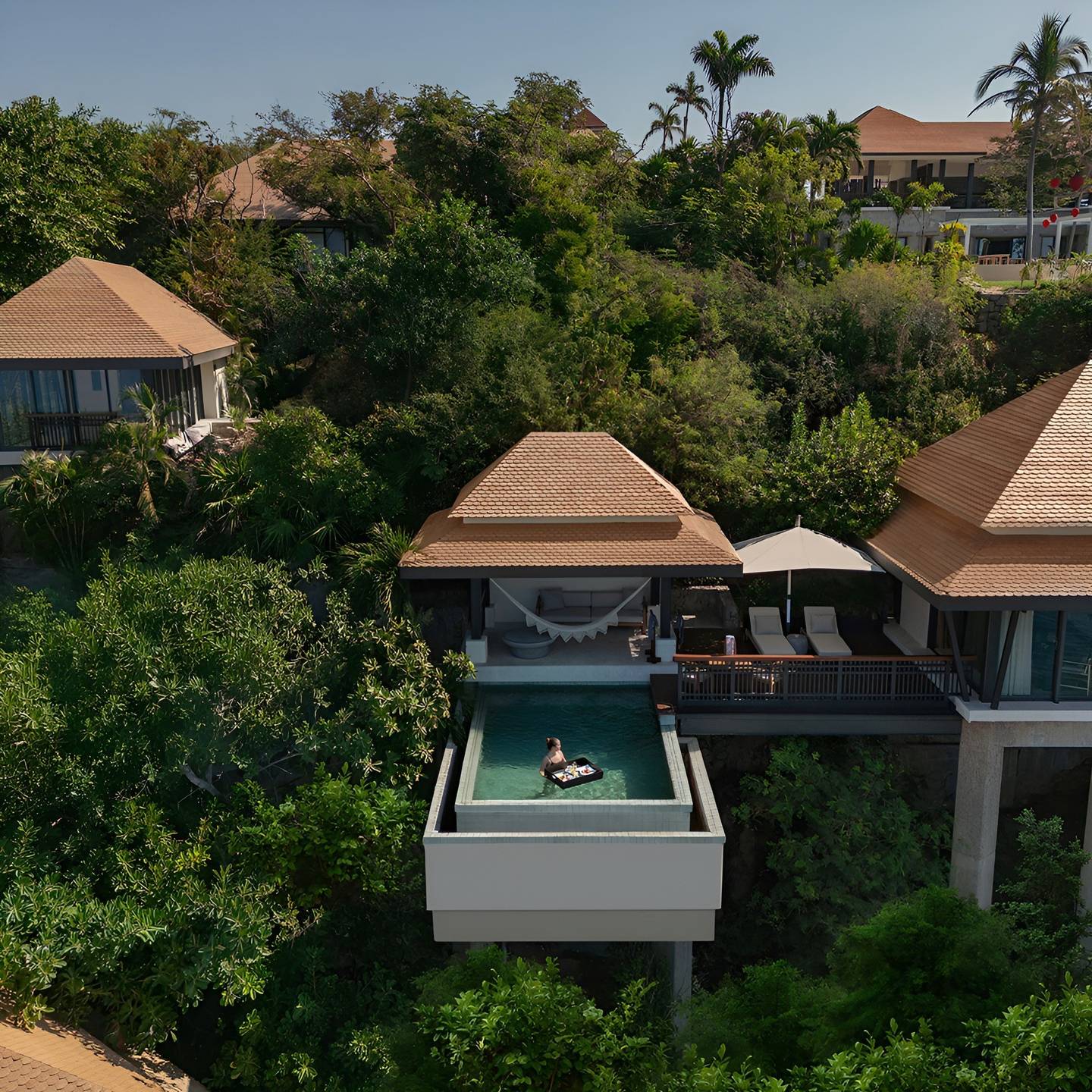 Hillside pool villa with a guest enjoying a floating breakfast