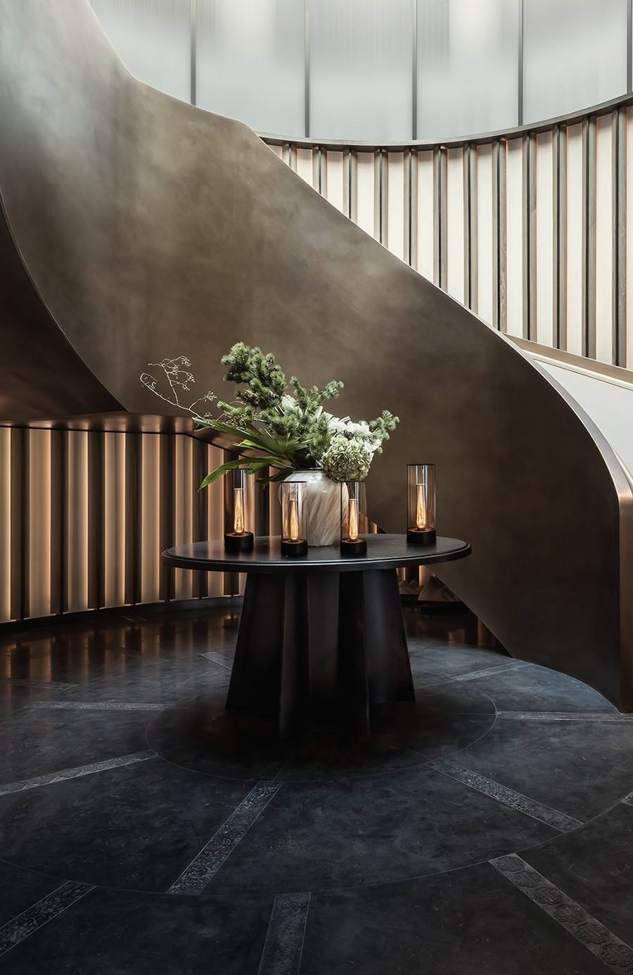 Spiral staircase above a lobby table with flowers and lanterns